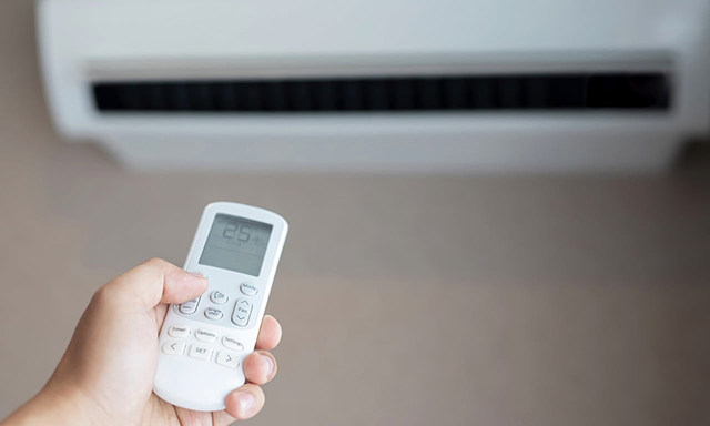 A hand holding a remote control for an HVAC system