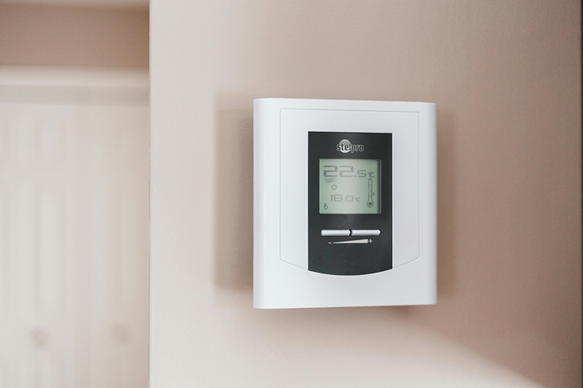 A white and black digital thermostat in a Phoenix home