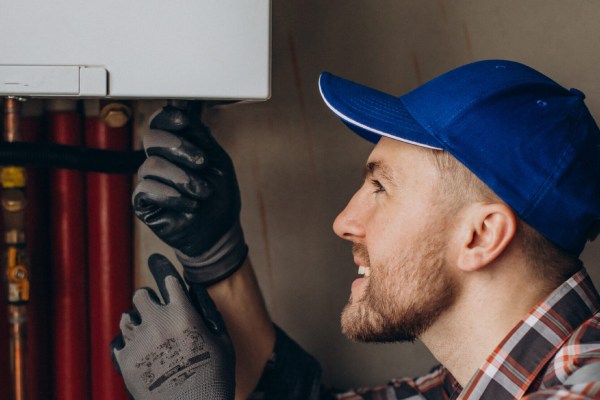 A technician wearing a blue hat and gloves for HVAC repair in Apache Junction