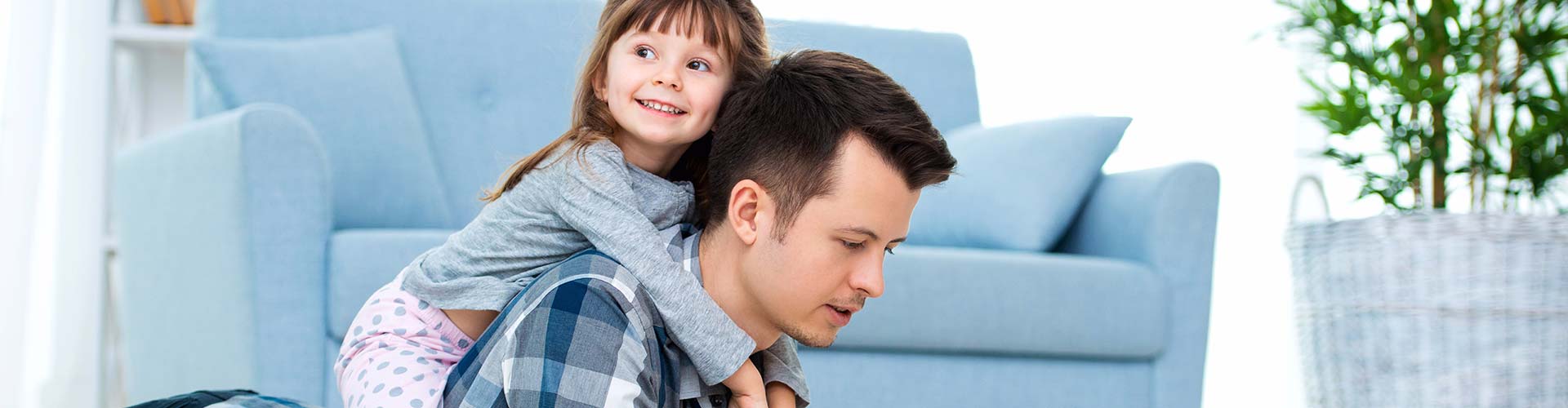 A child reading a book on their father’s back in a comfortable room